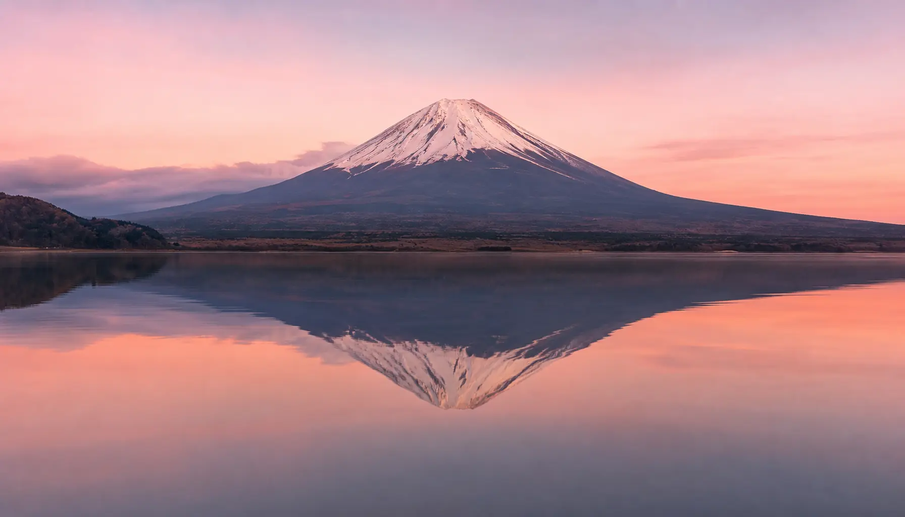 Mount Fuji mirrored in the still water of Lake Kawaguchi at dawn