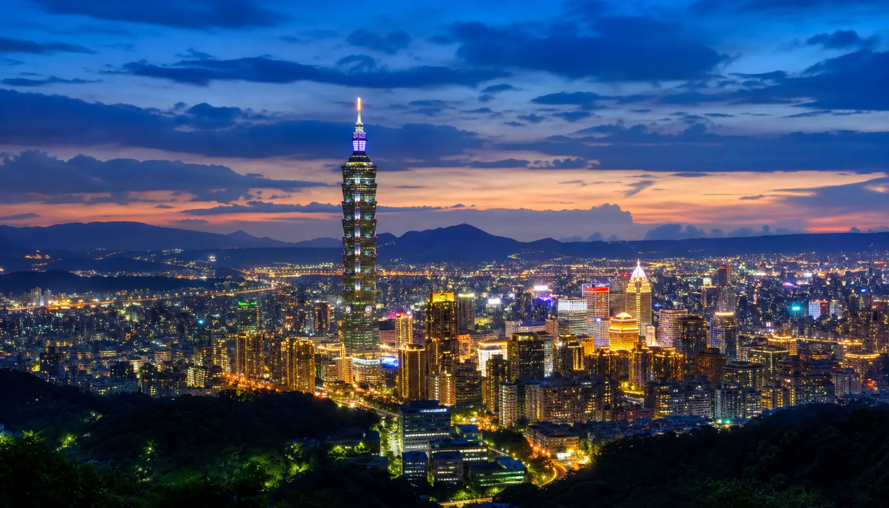 Taipei 101 towering over the city basin during blue hour