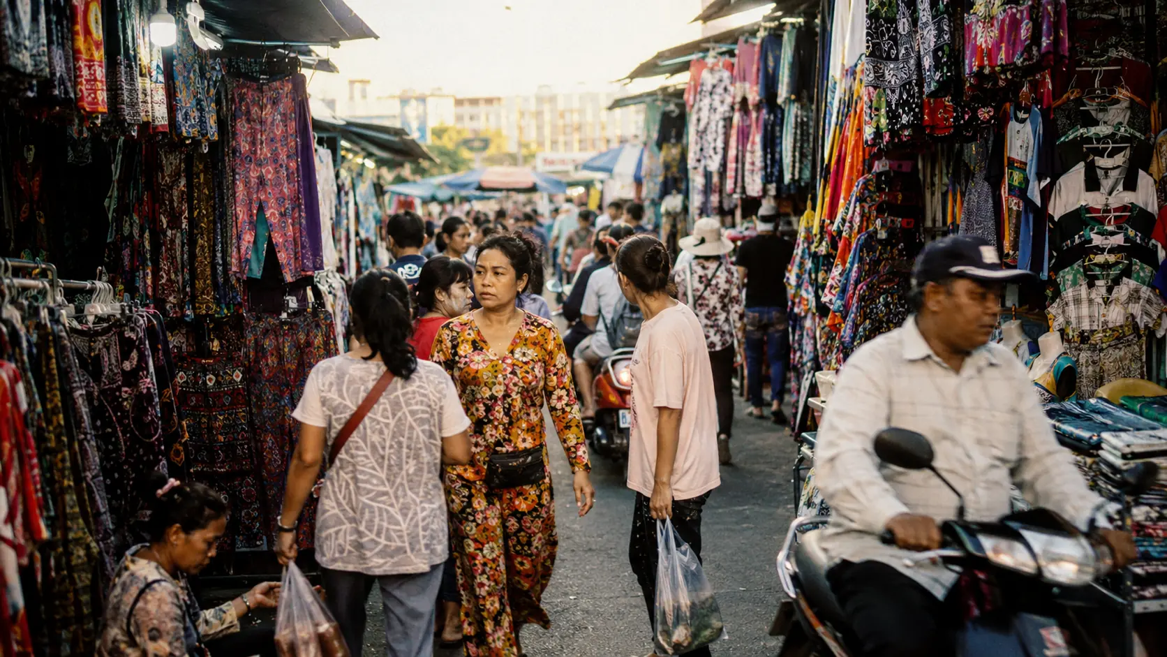 Handcraft souvenir stalls displaying carved wooden Buddhas, painted lacquerware and silk scarves at a Siem Reap market