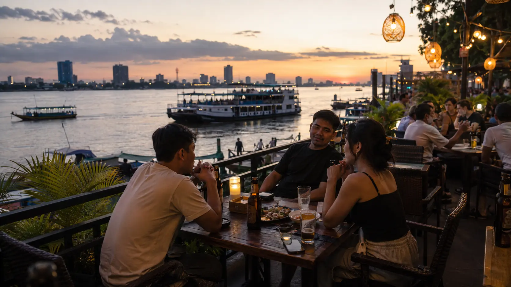 Open-front bar on the Mekong riverside in Phnom Penh, wicker chairs facing the water and Angkor Beer signs above the bartender