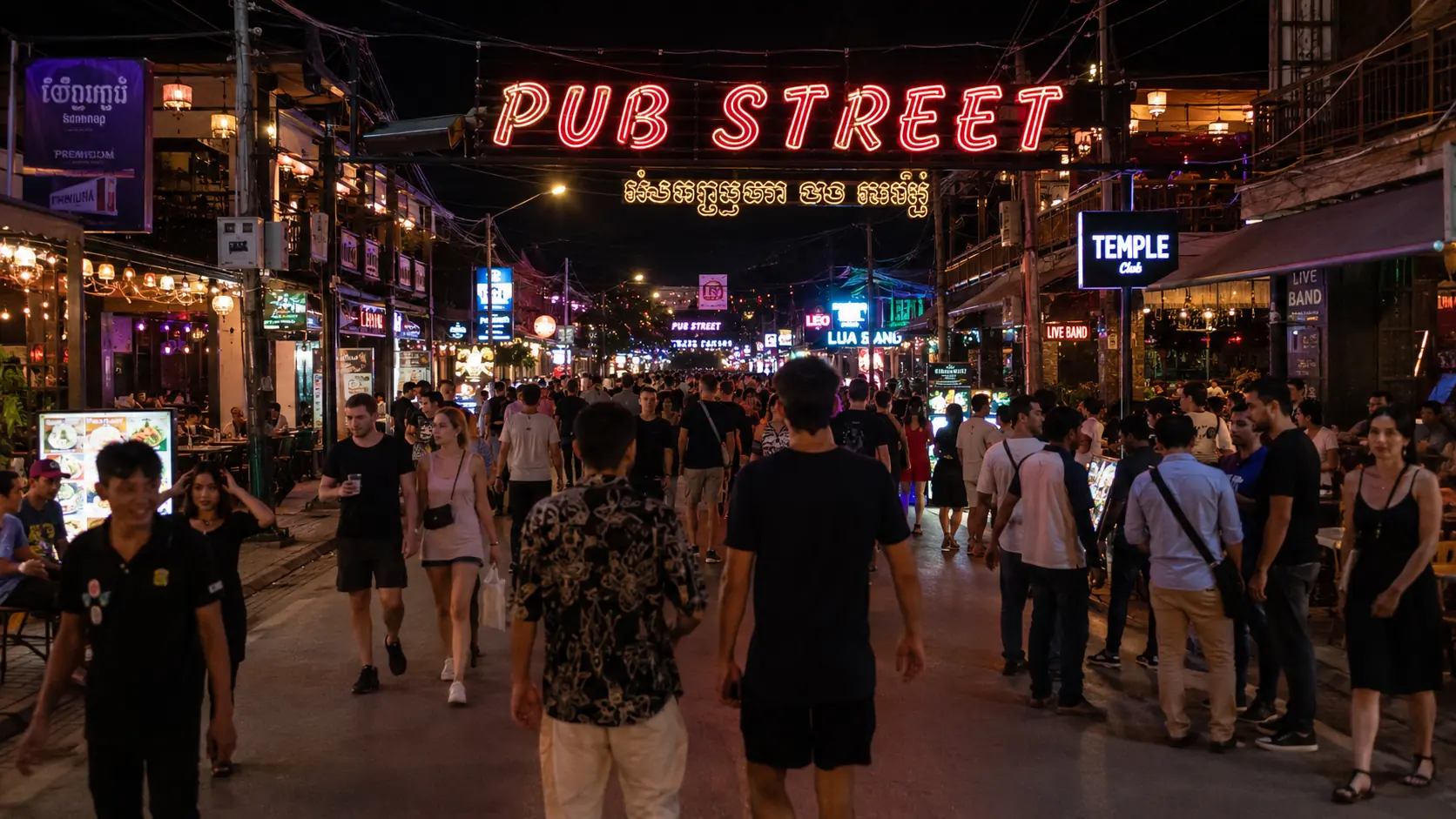 Pub Street in Siem Reap by night with red neon arches, crowded outdoor bars and tuk-tuks lining the pedestrian strip