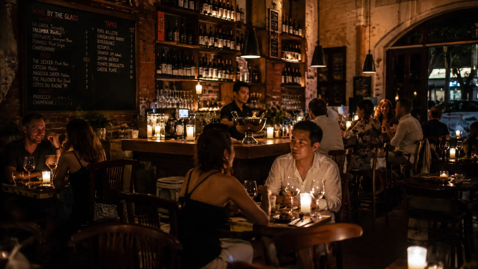 Wine and tapas bar in Phnom Penh with bottles displayed on backlit shelving, small plates of charcuterie and patrons at the marble bar
