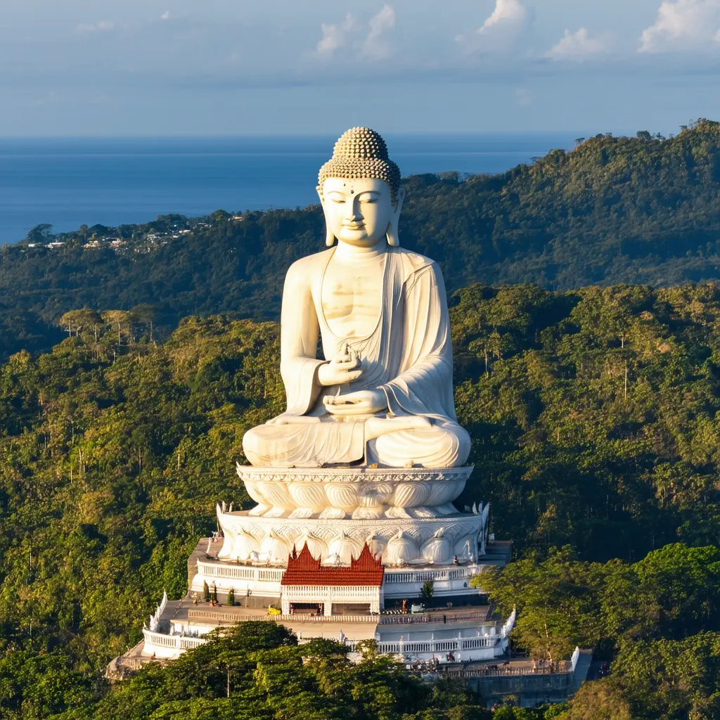 Big Buddha of Phuket on Nakkerd Hill, the forty-five-meter white marble seated Buddha overlooking forested hills and the Andaman Sea in warm golden afternoon light