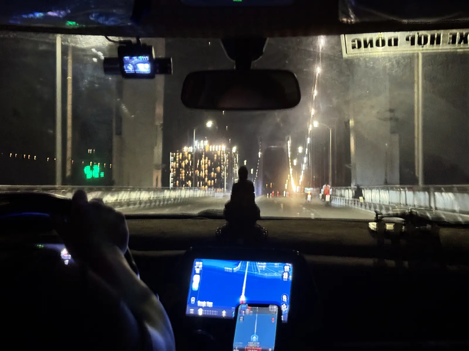 Crossing the bridge by car on a rainy night, dashboard navigation glowing